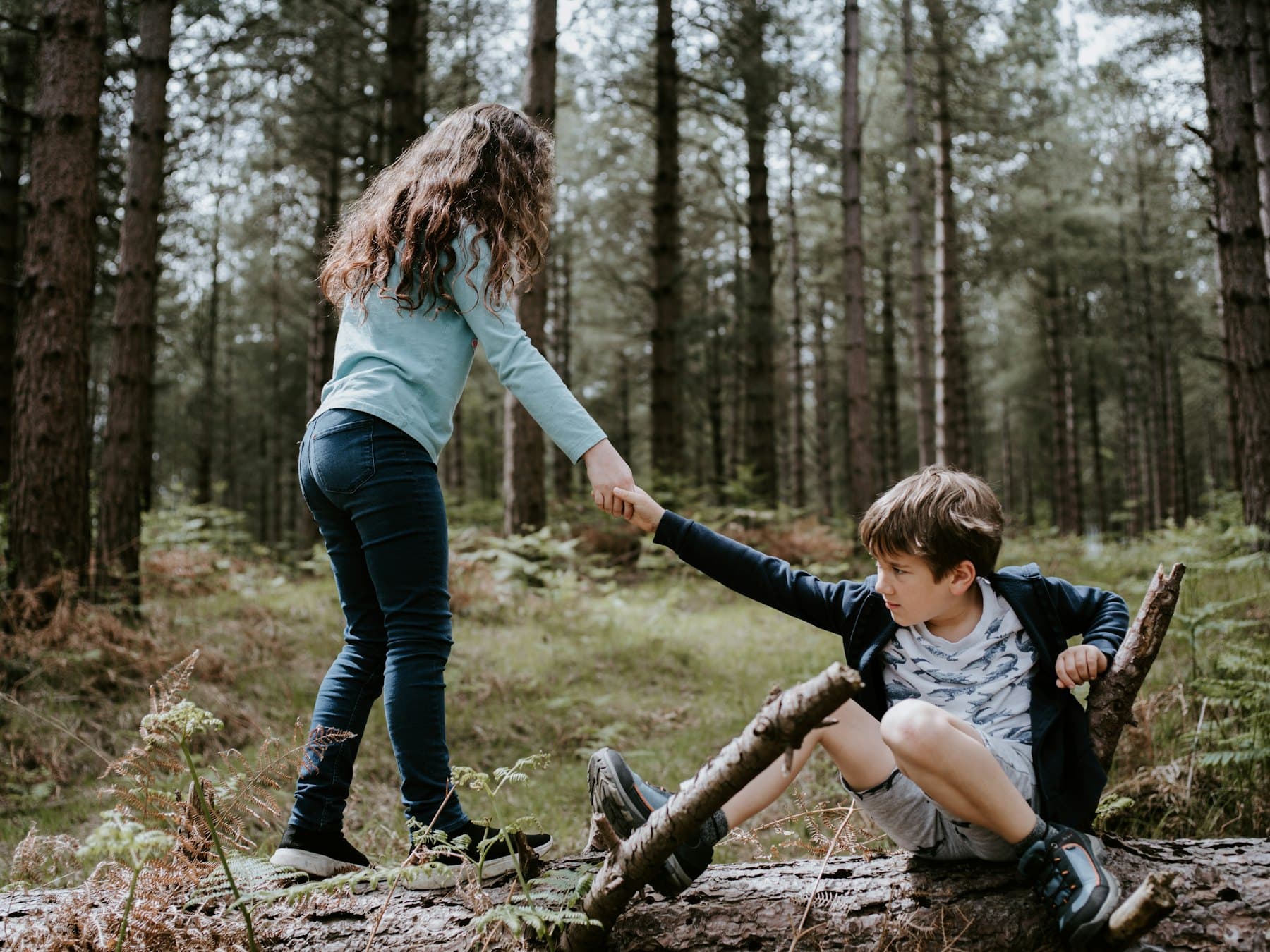 A boy and a girl playing on a tree log