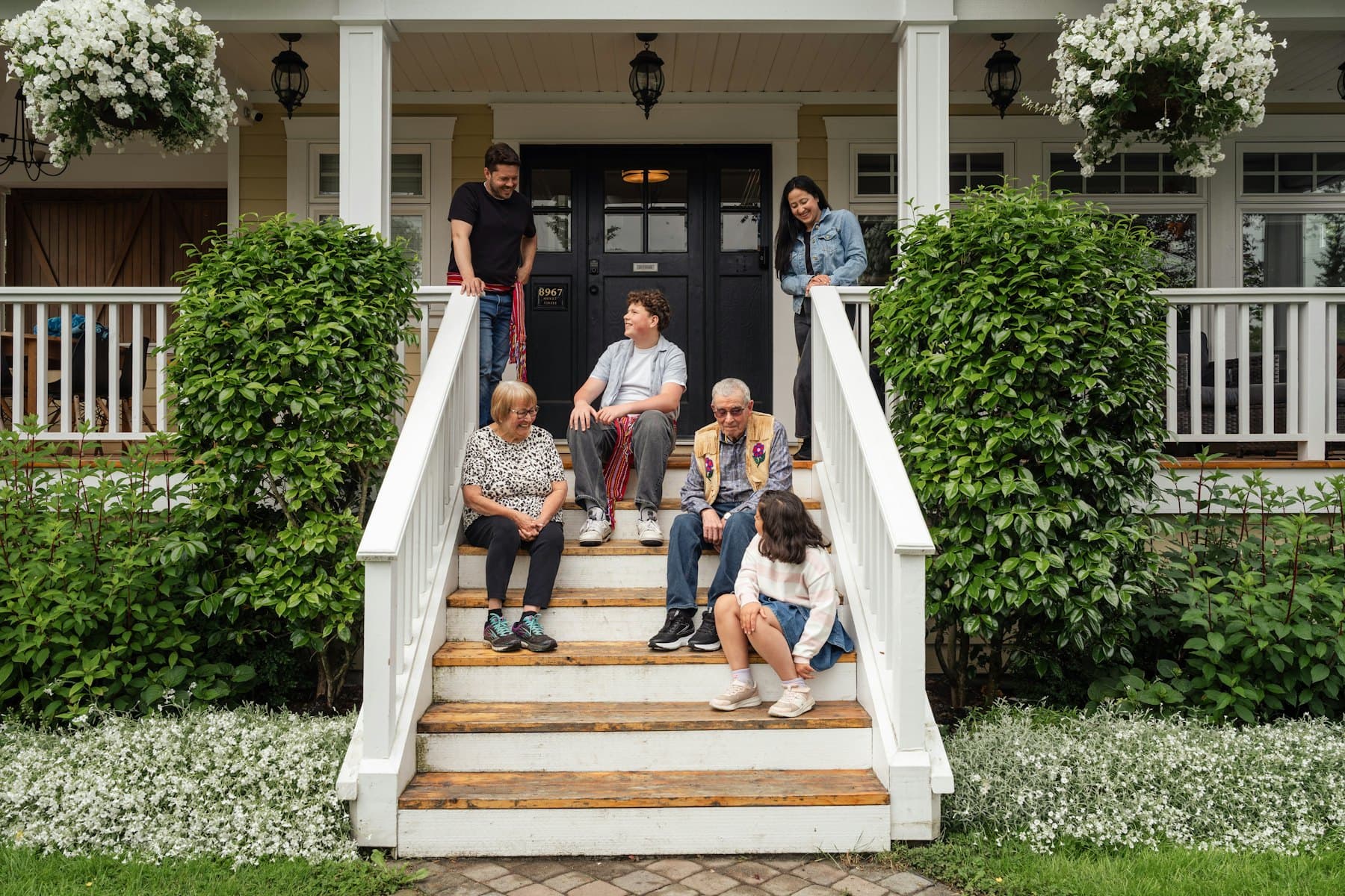 A family sitting on the steps of their porch