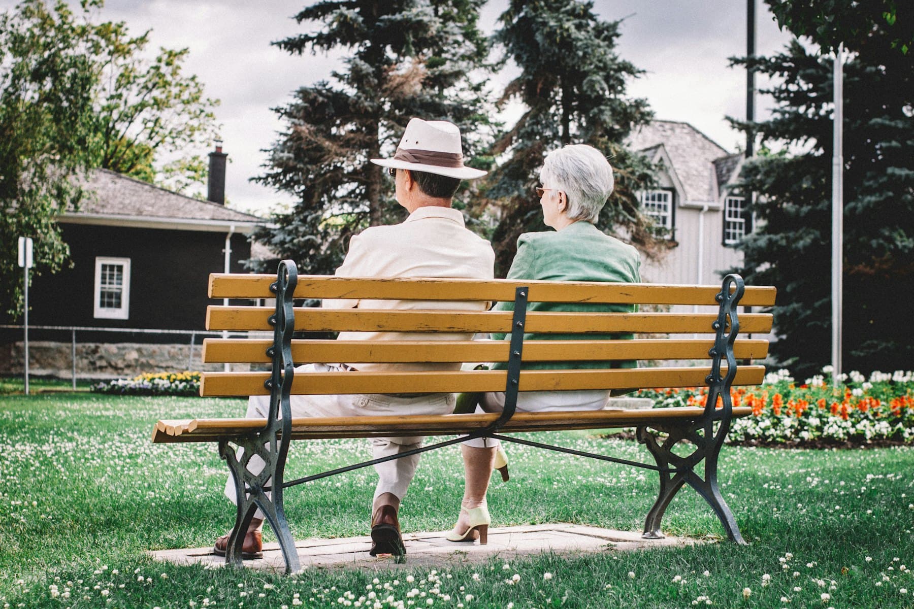 A man and a woman sitting on a wooden bench