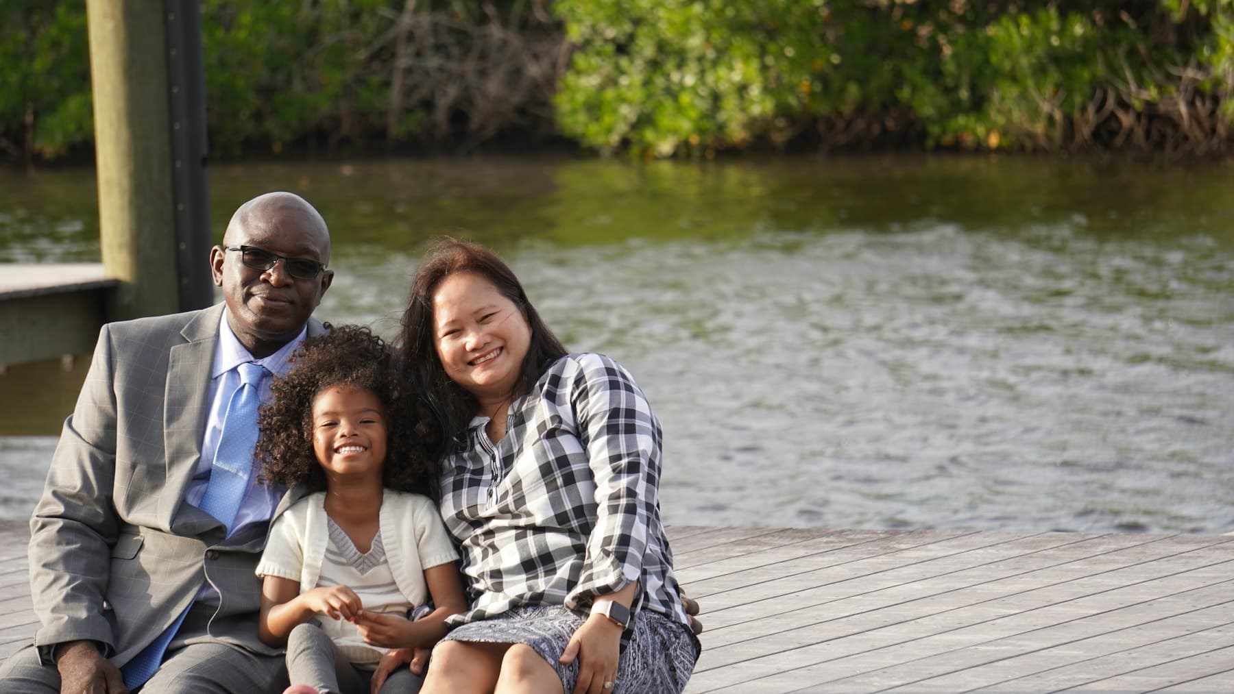 A man, woman and child sitting on a dock