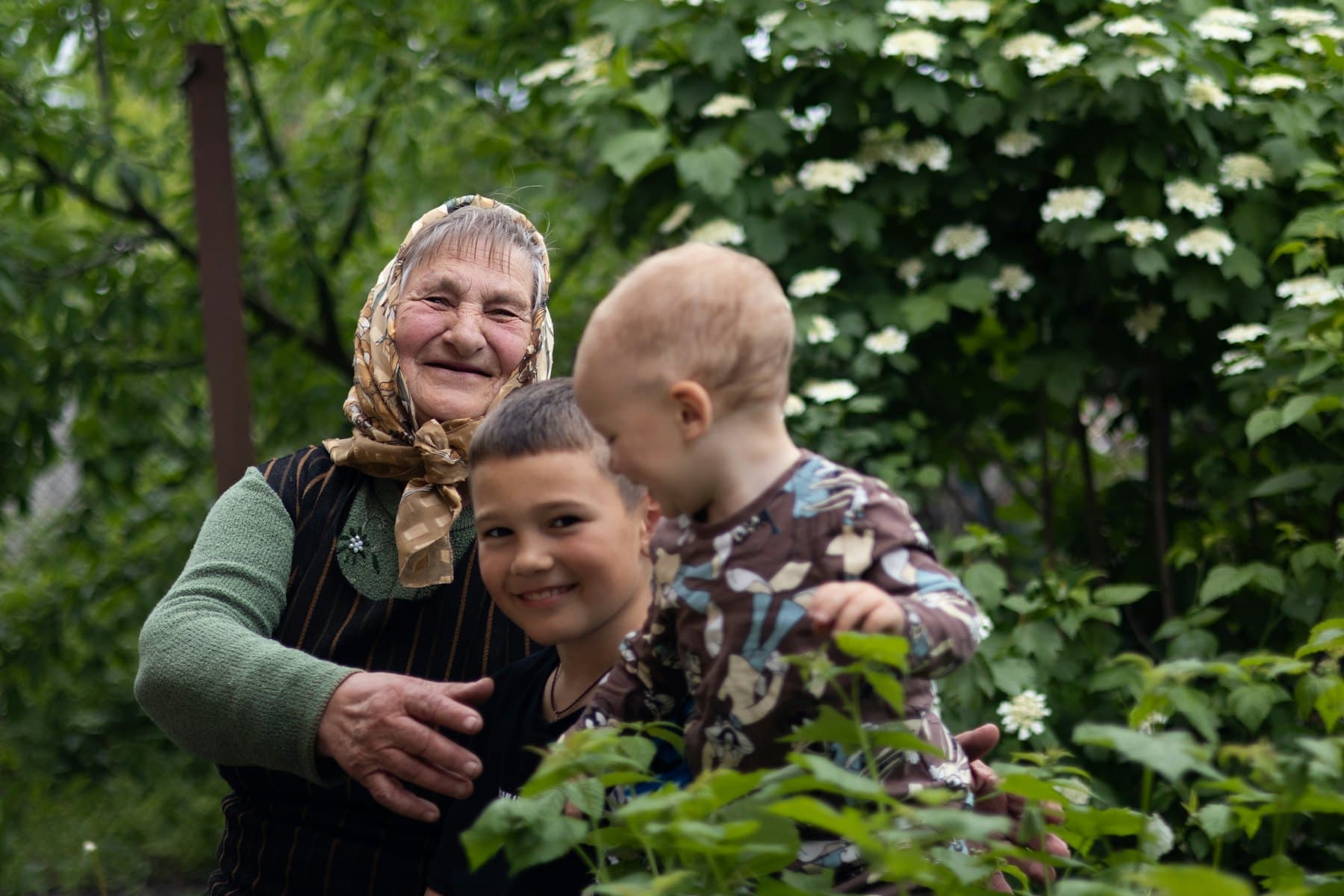 A woman and two children standing in a garden