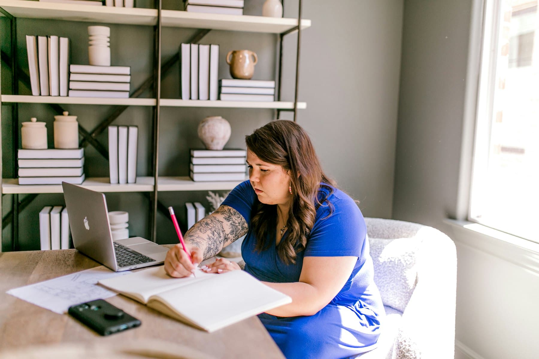 A woman writing in a notebook at her home desk