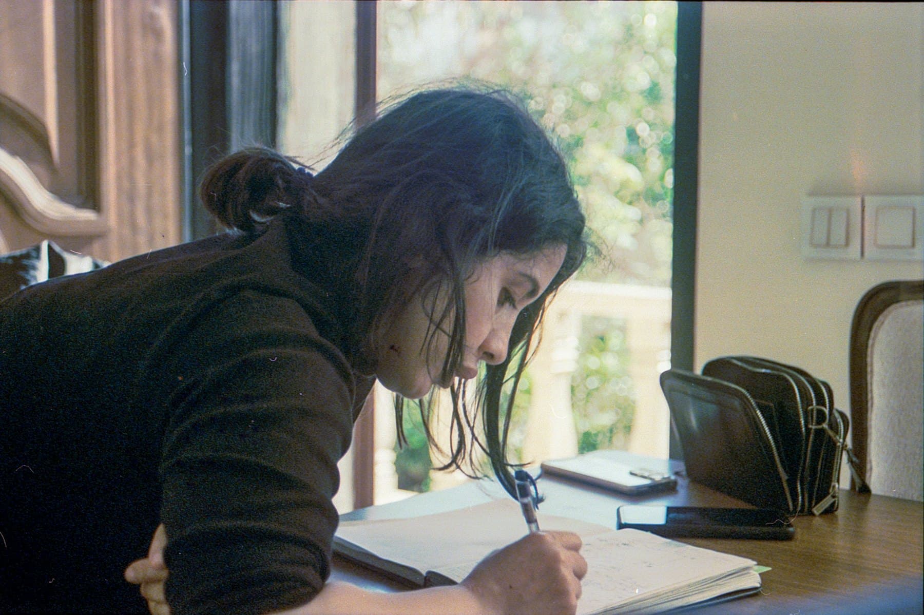A woman writing in a notebook at a table