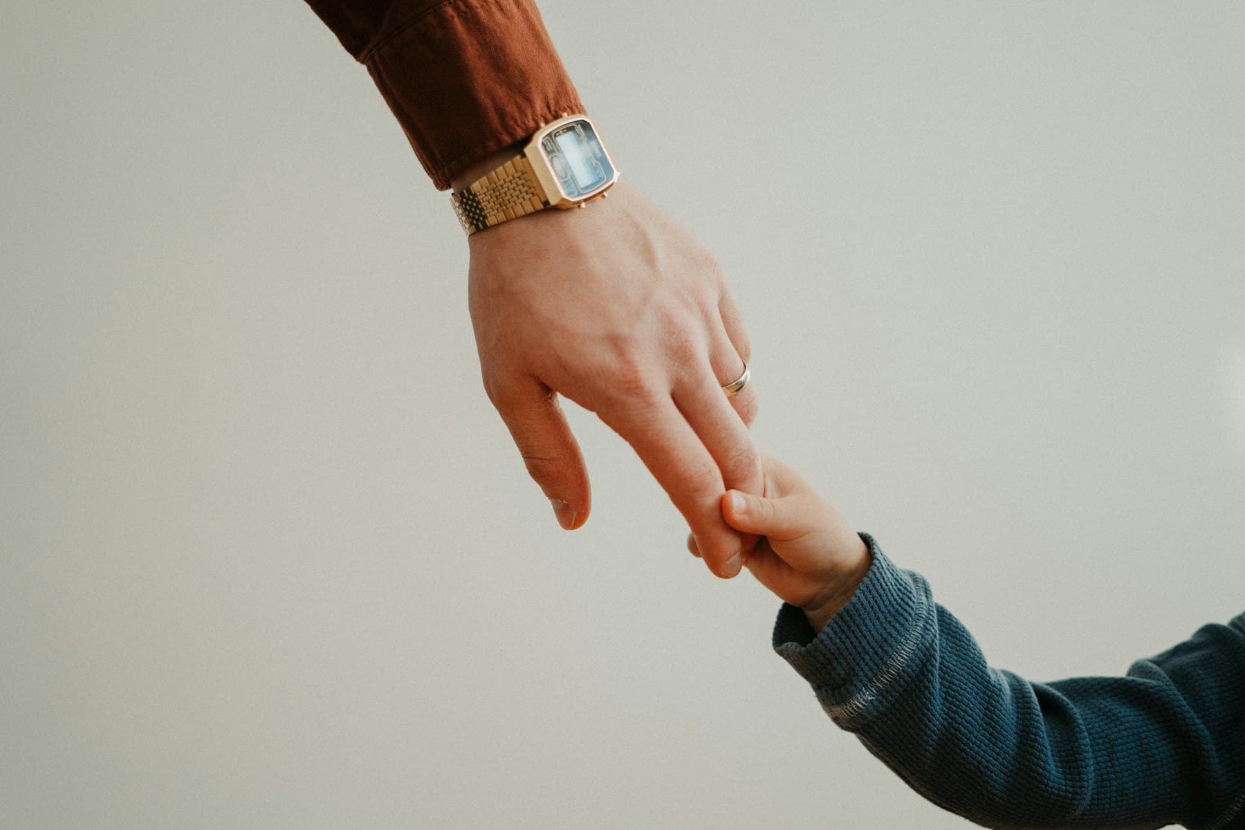 An adult holding a child's hand