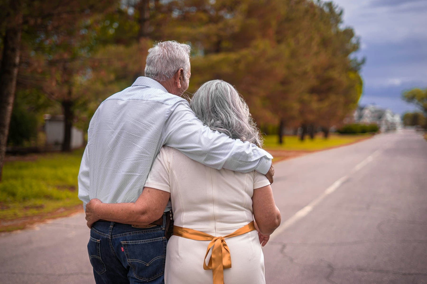 An older couple walking arm in arm down a road