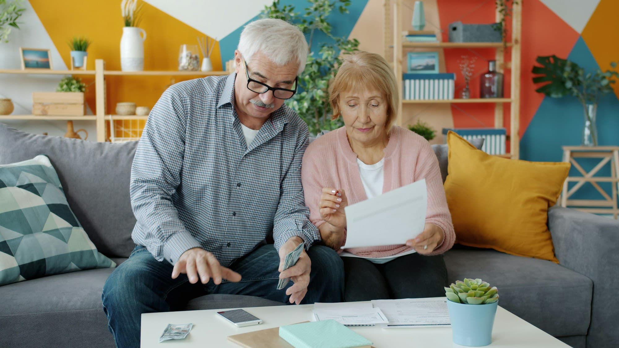 An older couple reading through paperwork together on their couch