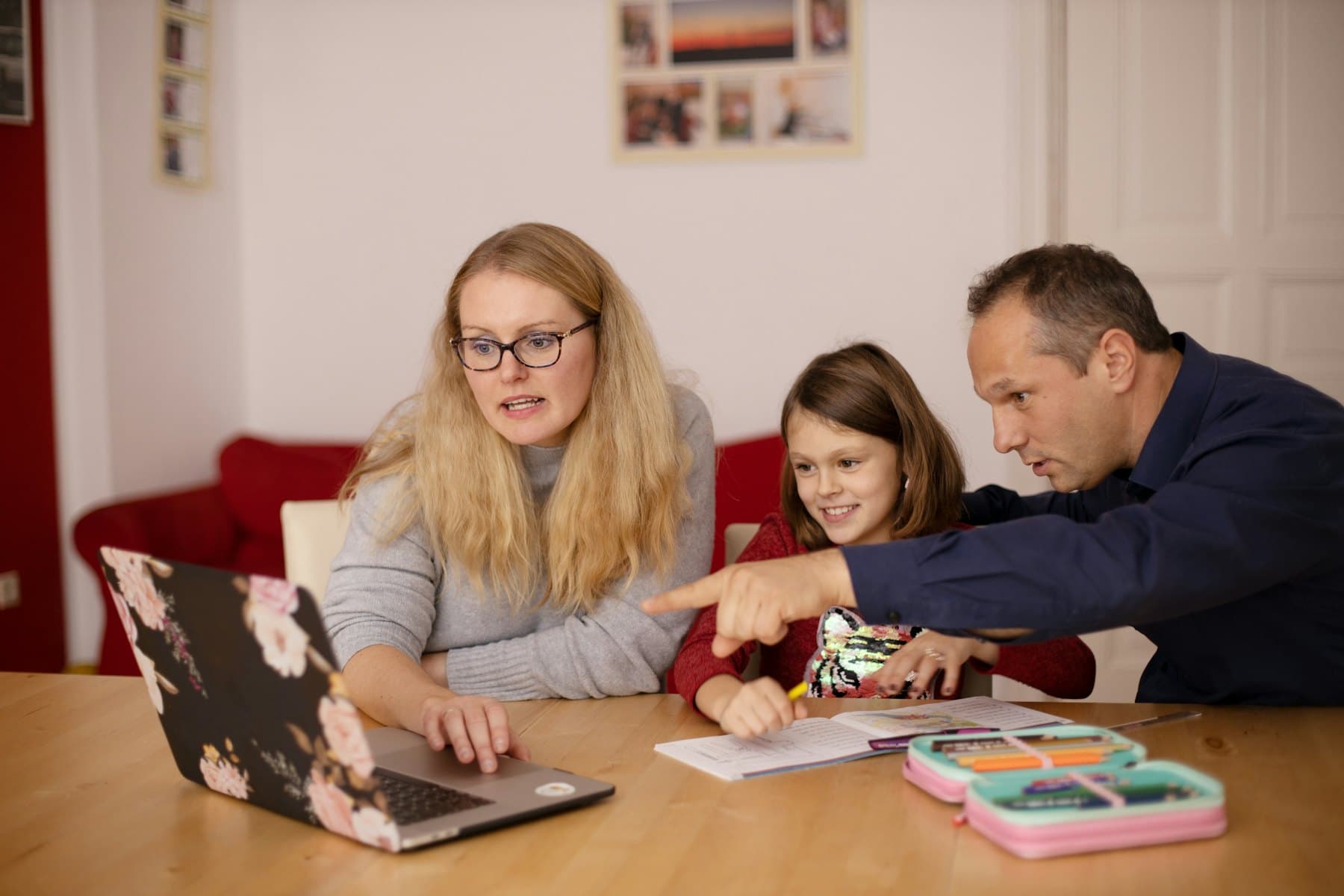 Parents helping a child with schoolwork on a laptop