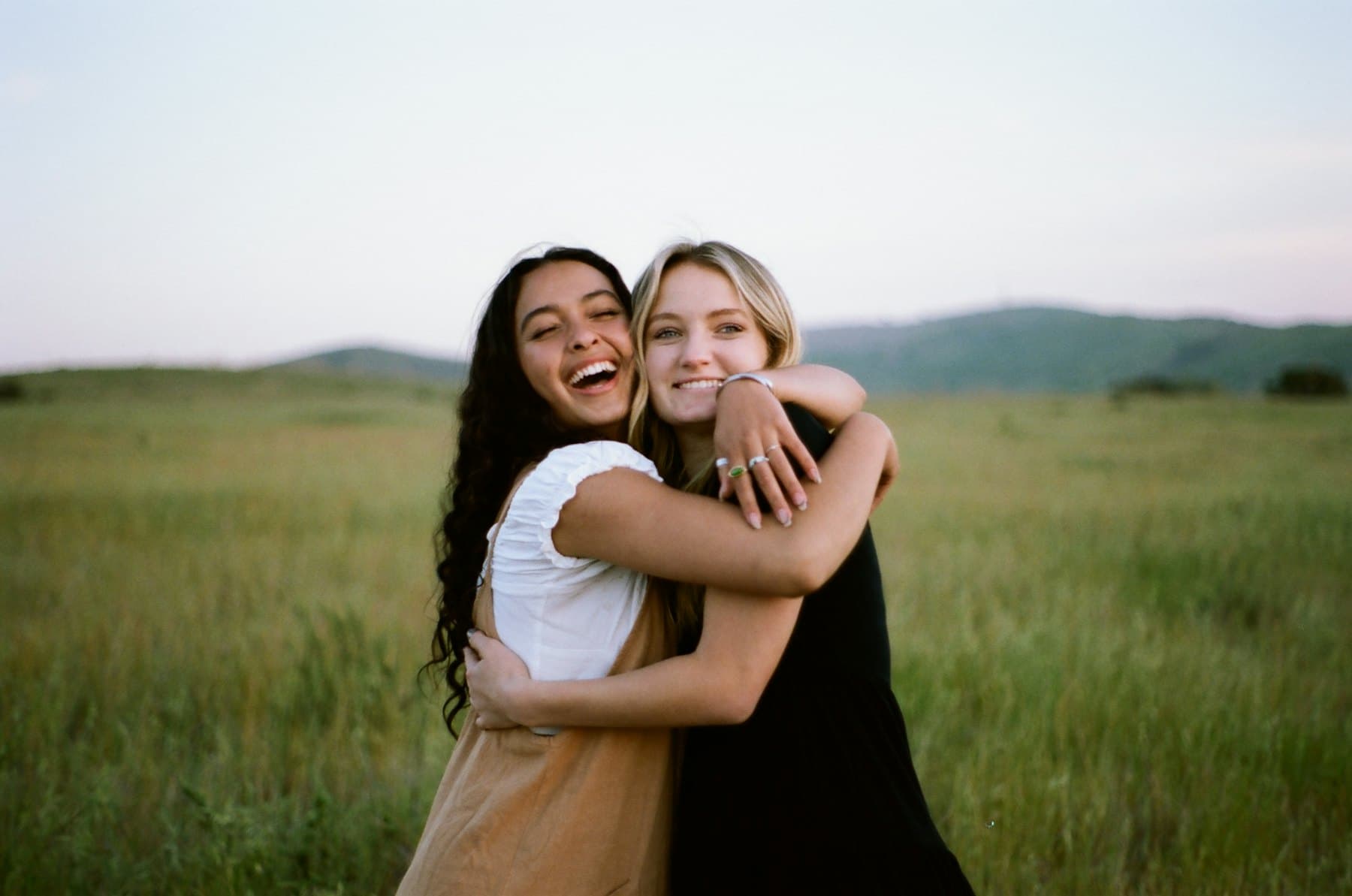 Two women hugging in a grassy field