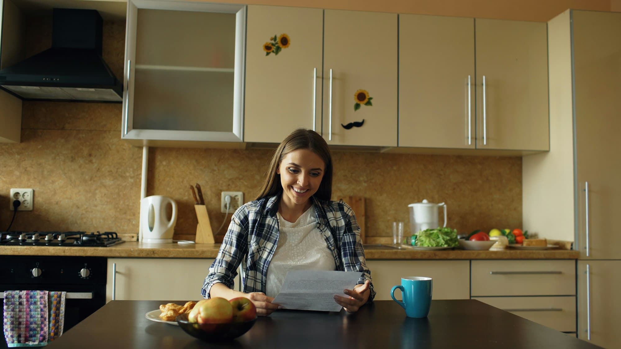 A woman reading a letter at her kitchen table