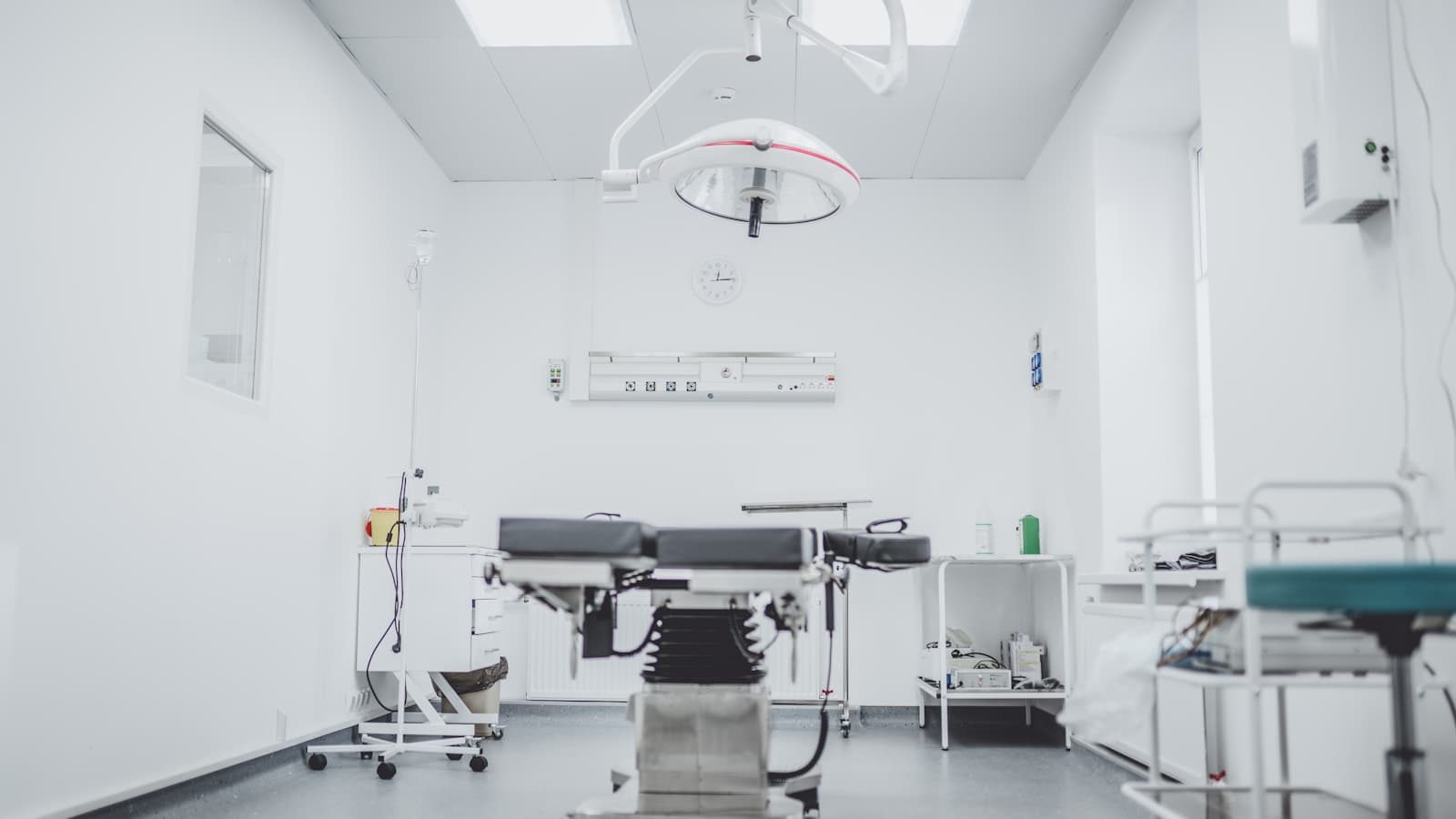 Empty hospital procedure room with surgical light, IV pole, and adjustable bed, representing the inpatient setting where heparin-induced thrombocytopenia develops and is treated