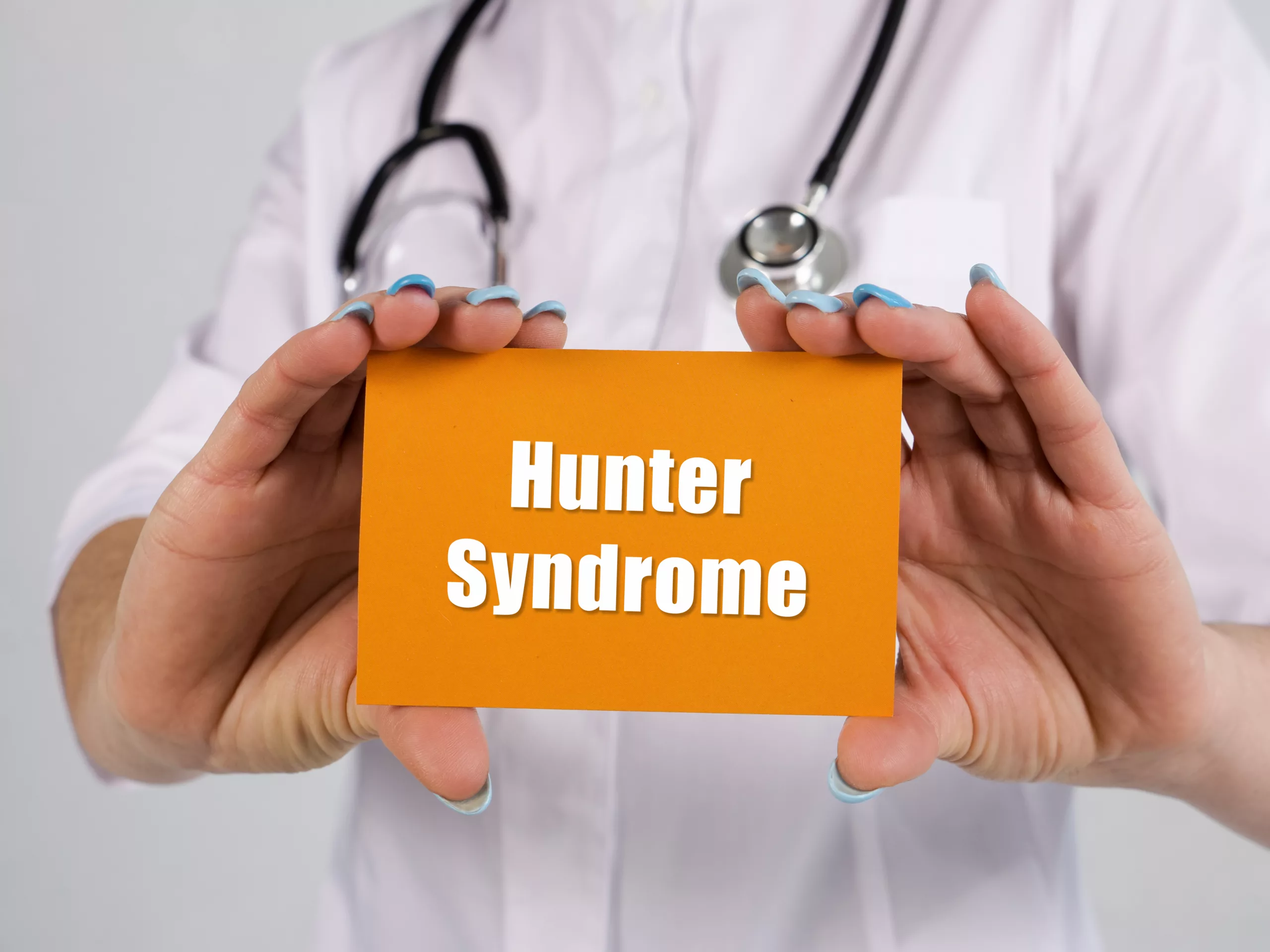 Medical professional holding an orange card that reads Hunter Syndrome