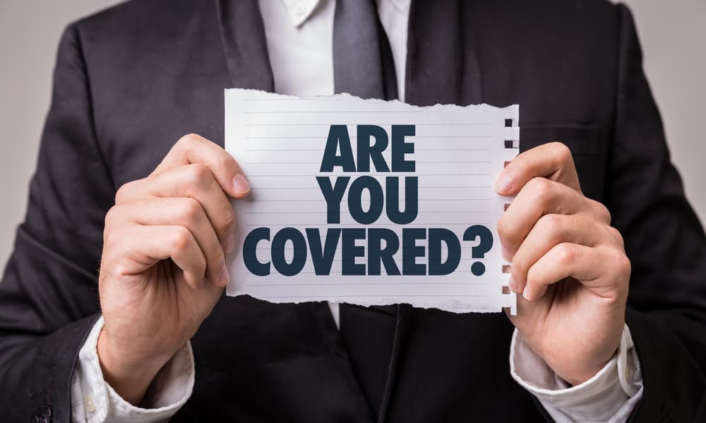 Person in a suit holding a torn piece of paper that reads Are You Covered, representing insurance coverage questions for rare disease patients