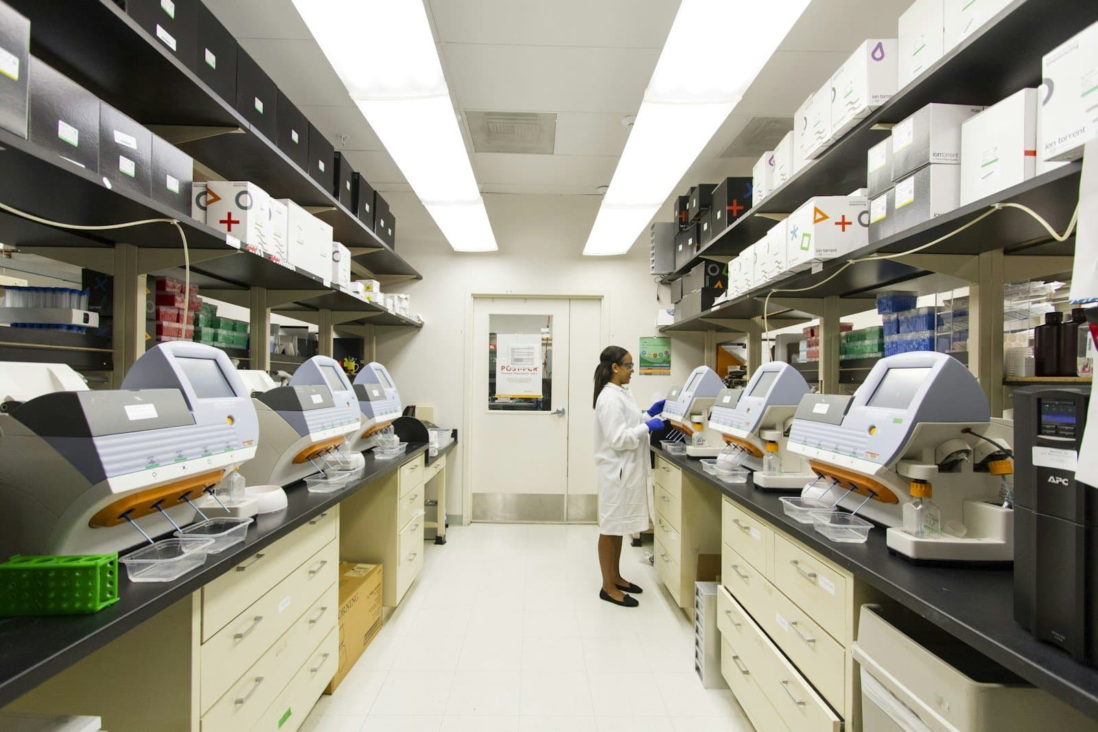 A researcher in a white coat working at a bench in a hospital laboratory.