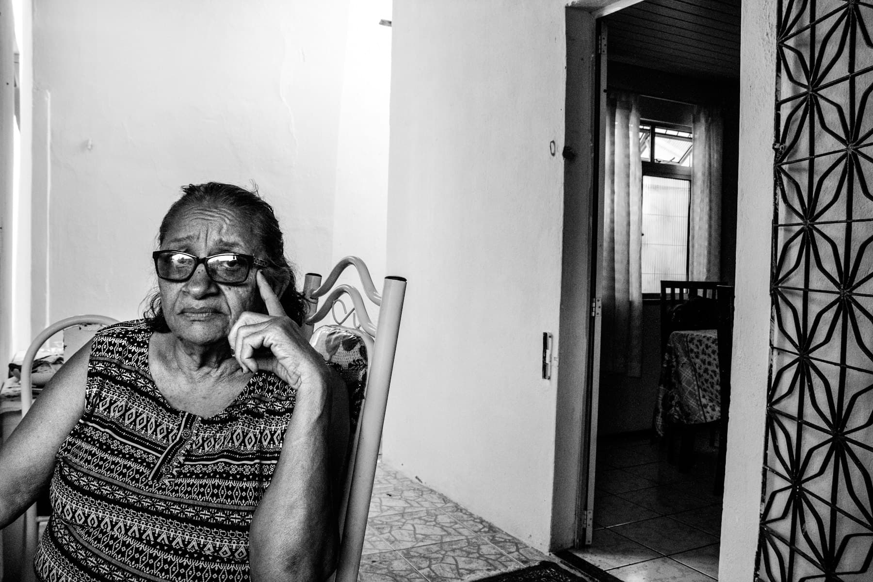 An older woman with glasses sitting in a chair