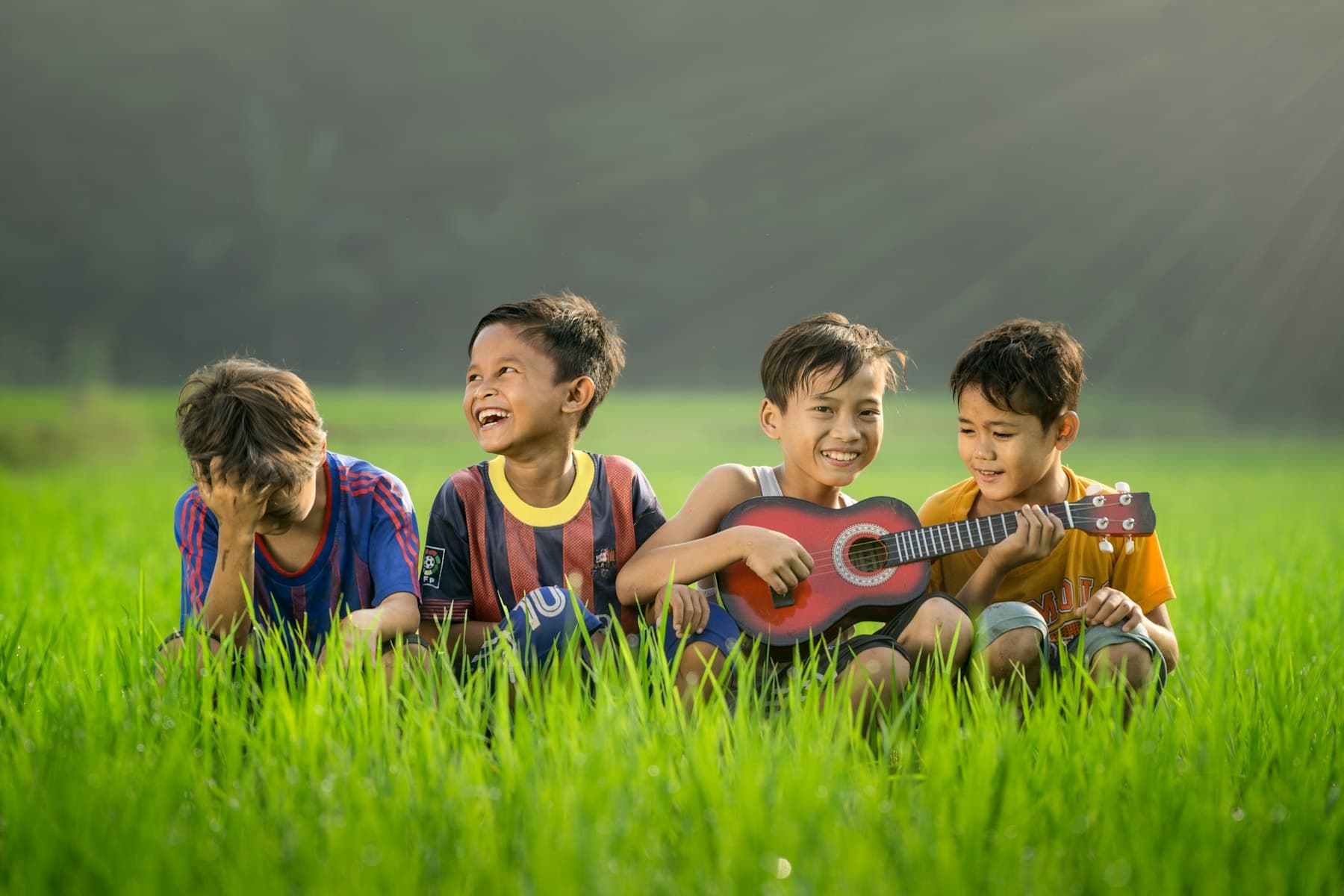 Four boys laughing on the grass