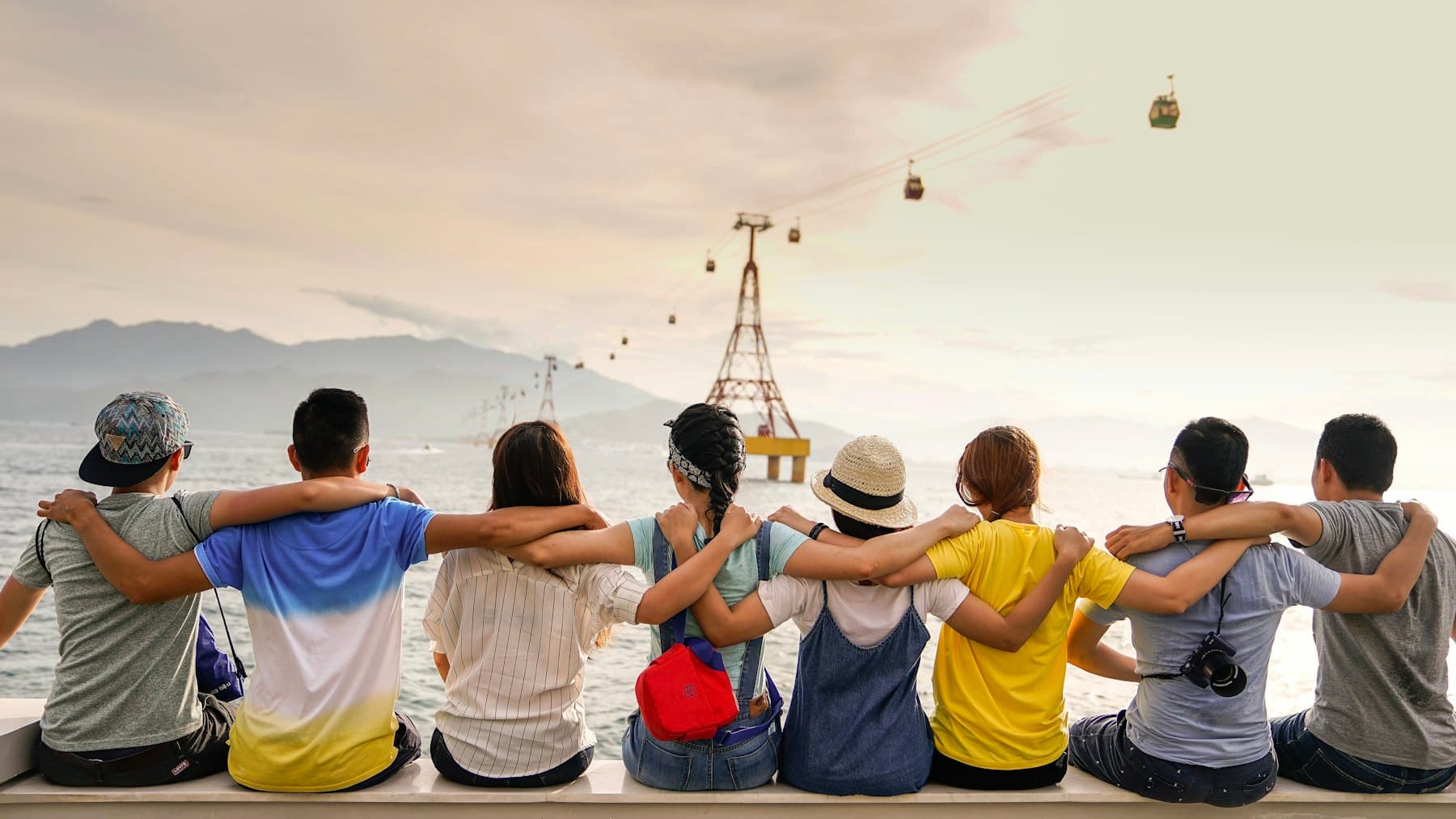 Friends sitting on a wall with their arms around each other