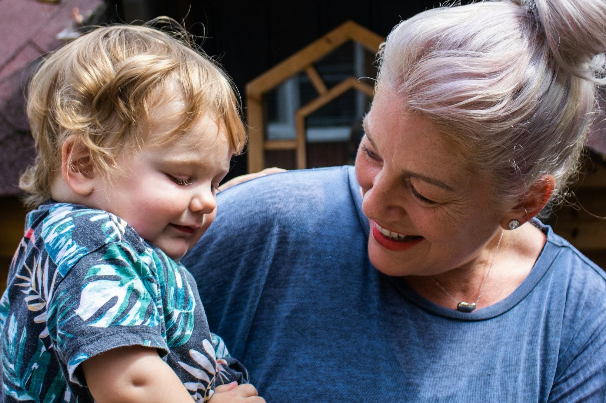 A grandmother smiling at the toddler she is holding