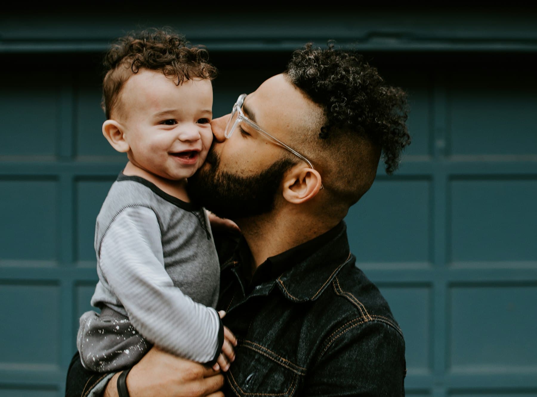 A man kissing the cheek of the baby he is carrying