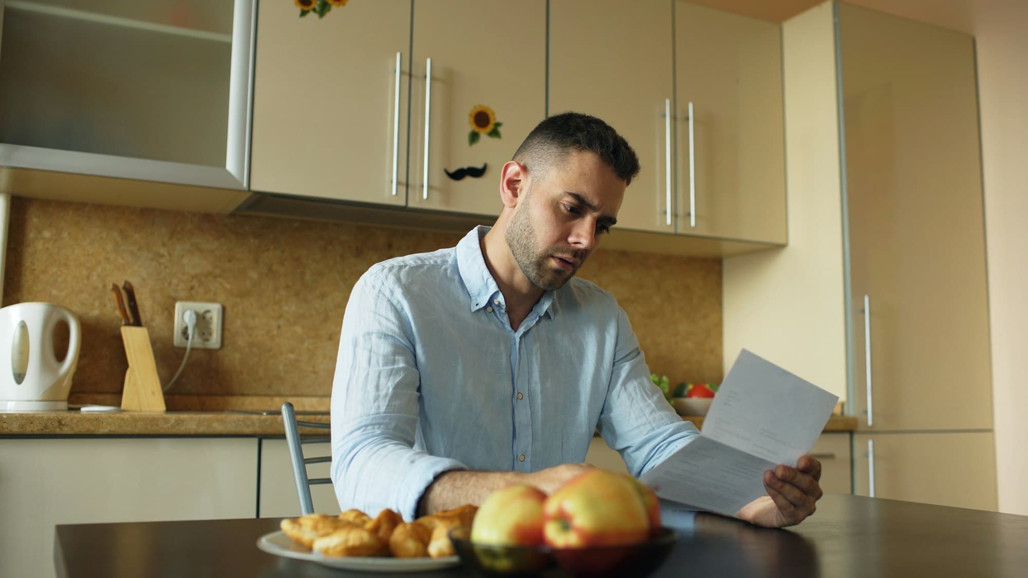A man reading a letter at his kitchen table