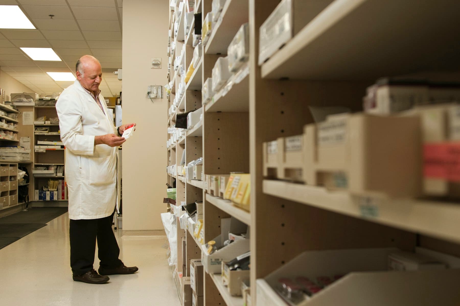 A pharmacist standing by the pharmacy shelves